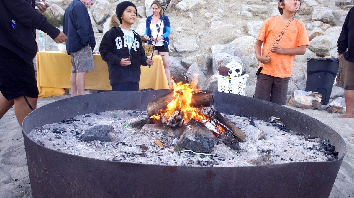 From left, Lawrence Grant, 5, and Andreas Gonzalez, 7, toast their marshmallows at Olde Port Beach firepits during a beach bonfire for vacation owners at the nearby San Luis Bay Inn.