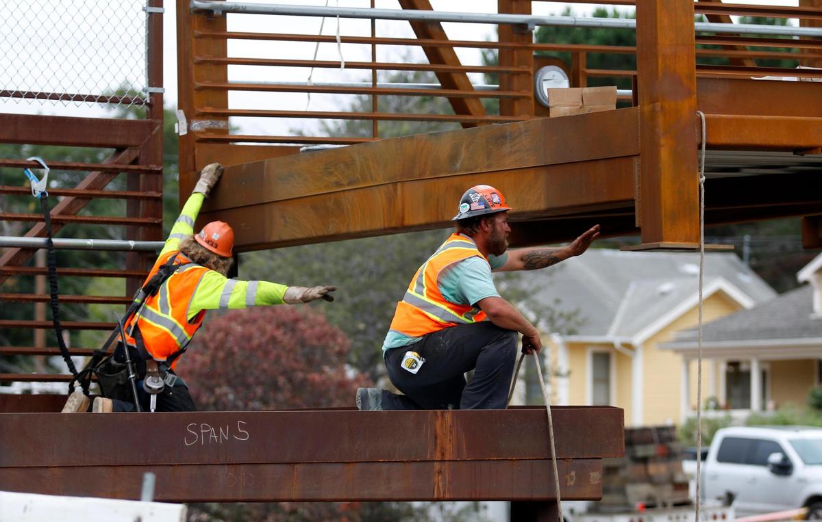 Workers guide San Luis Obispo’s new pedestrian-bicycle bridge into place at Pepper Street and Phillips Lane on Friday. The bridge is a key part of the city’s Railroad Safety Trail. Souza Construction is building the bridge with an assist from Bragg Crane.