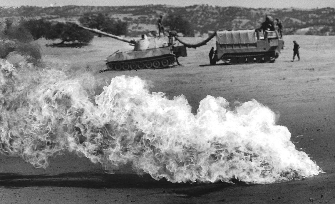 Rather than store them, excess gunpowder bags are burned at the end of target practice at Camp Roberts. Behind is a self-propelled 155 mm howitzer. Photo published Aug. 9, 1989.