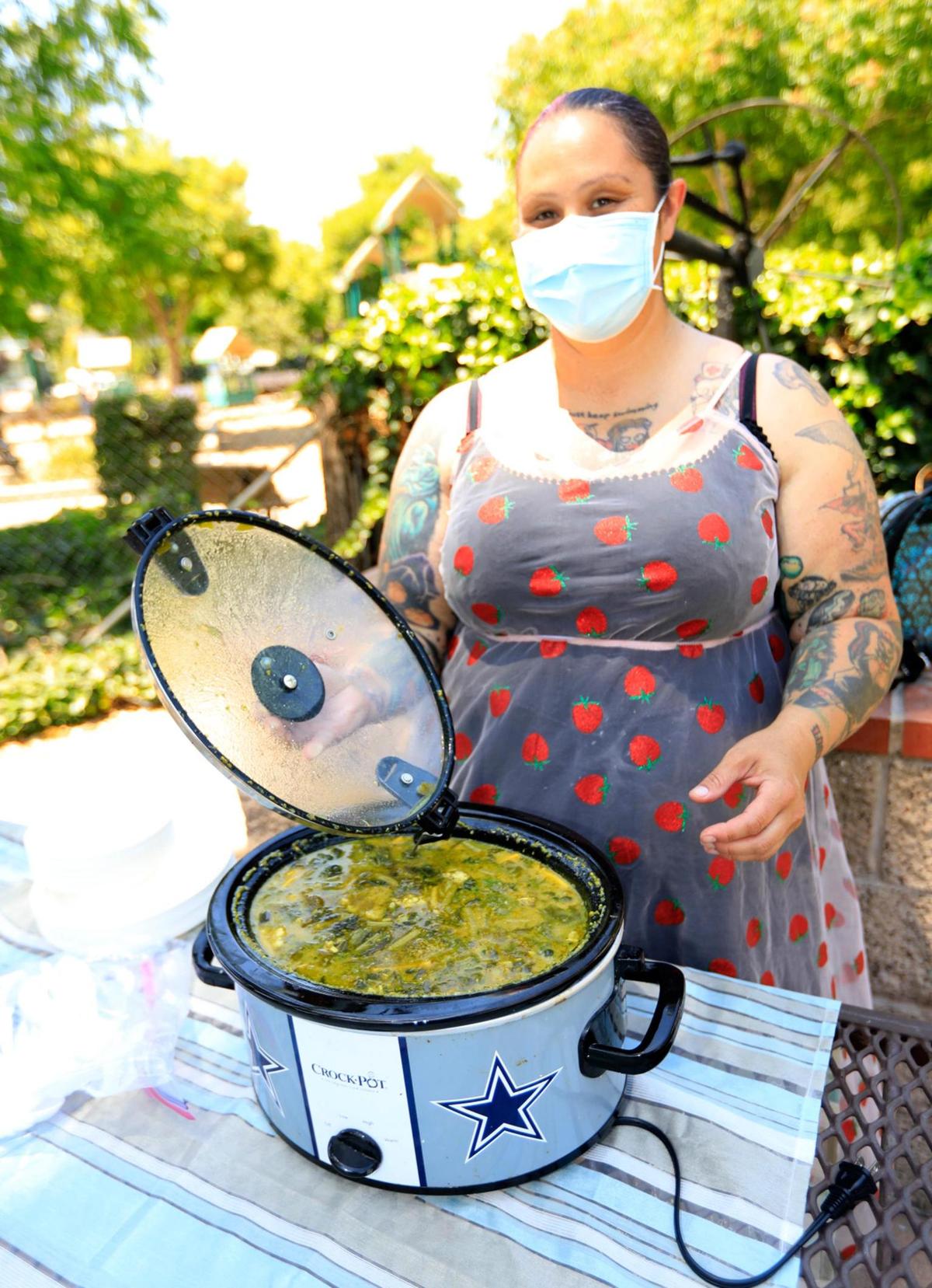 Michelle Mankser sets up a table in Mitchell Park with a chicken curry stew, salad, fresh fruit and water.