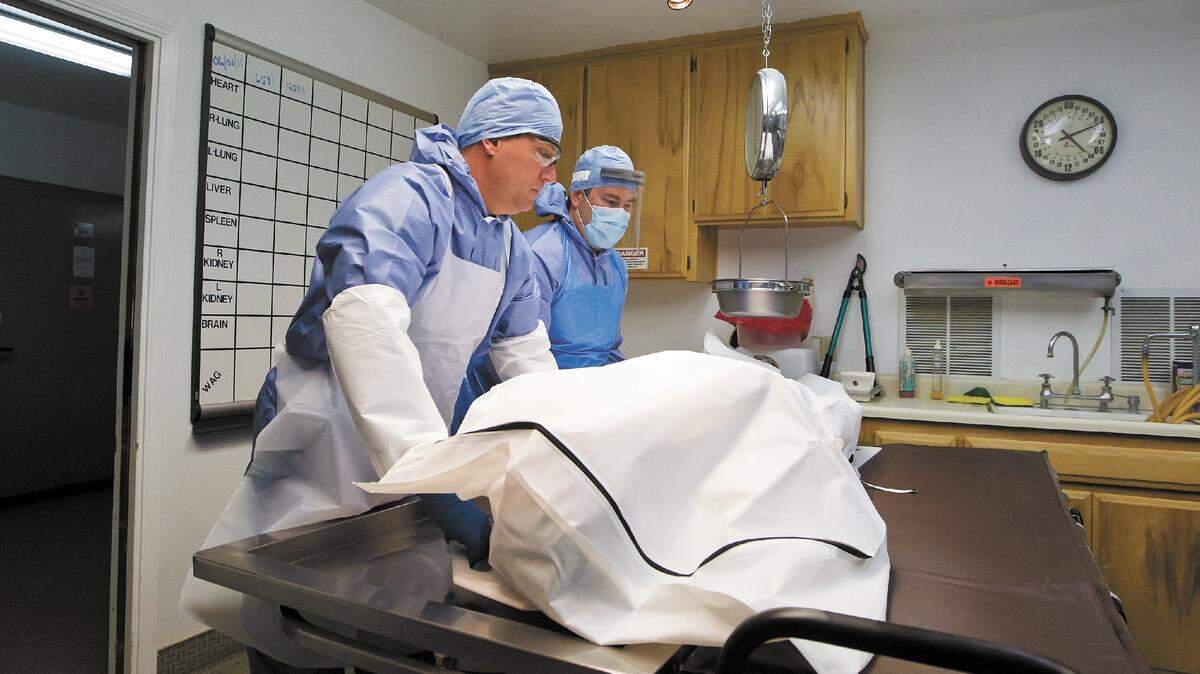 Coroner's investigators Jeff Nichols, left, and Stuart MacDonald prepare to perform an autopsy at the Los Osos Valley Mortuary.