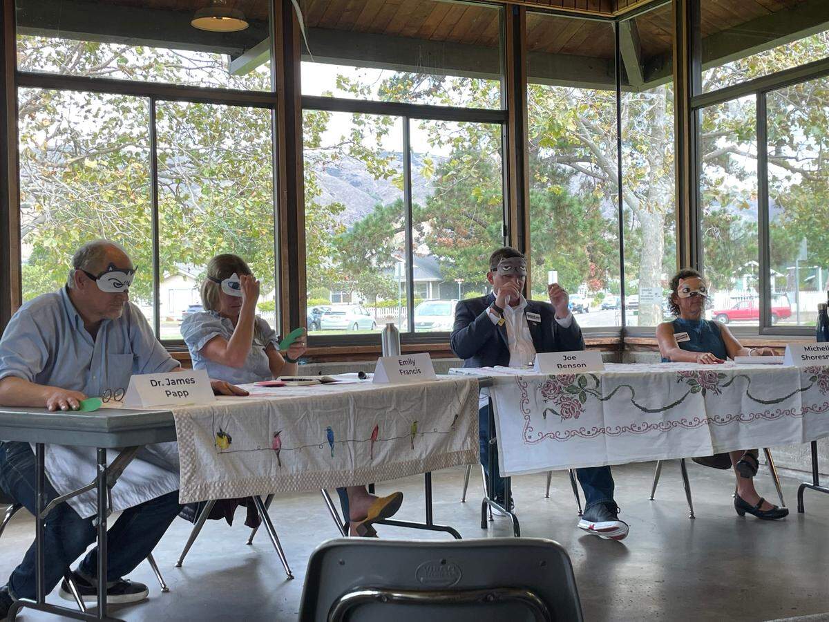 San Luis Obispo City Council candidates put on sleep masks as blindfolds to play a game of San Luis Obispo-related trivia at an election forum on Sunday, Sept. 18, 2022.