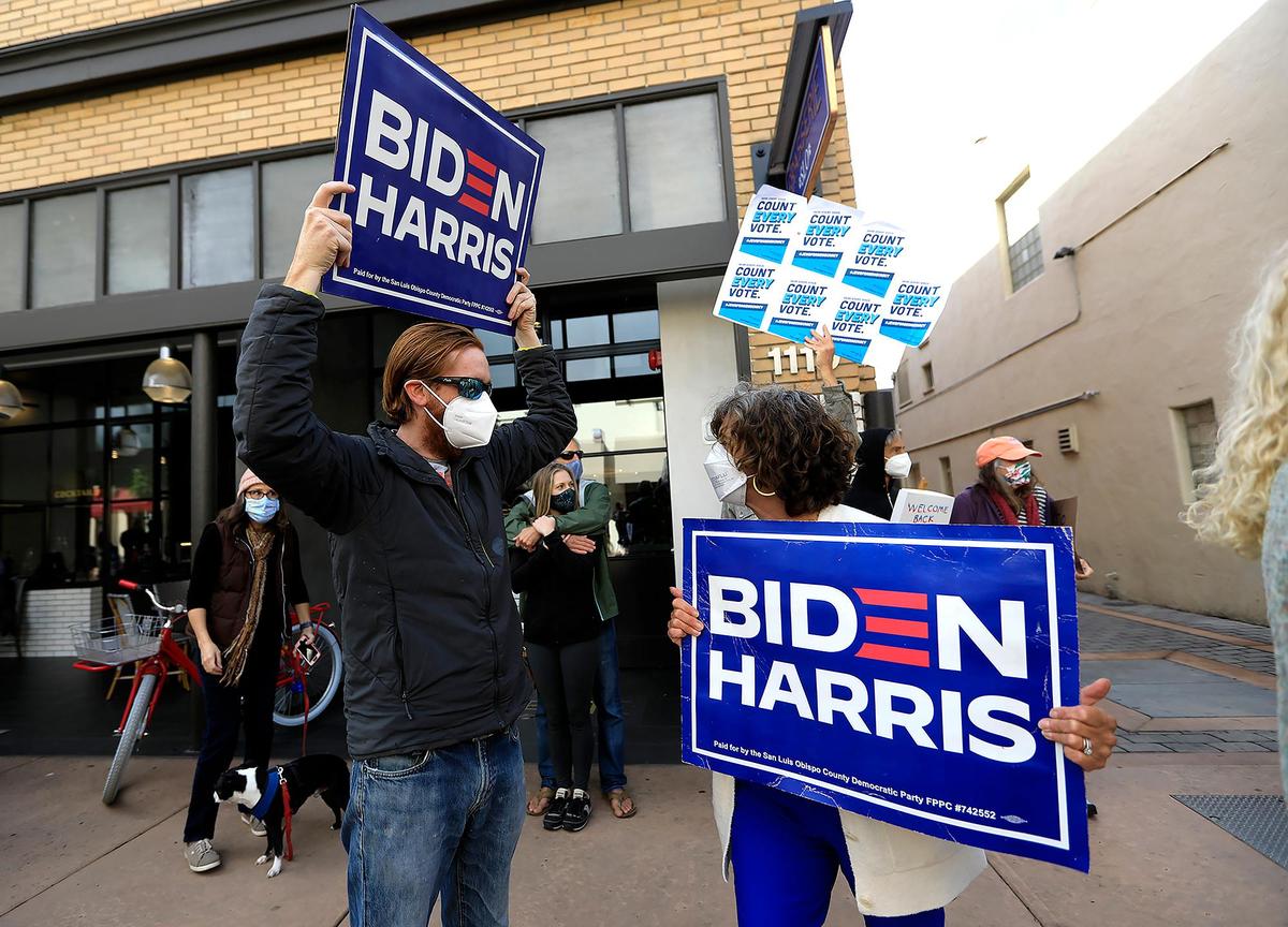 Biden-Harris supporters hold up signs during a celebration Saturday on Garden Street in San Luis Obispo.