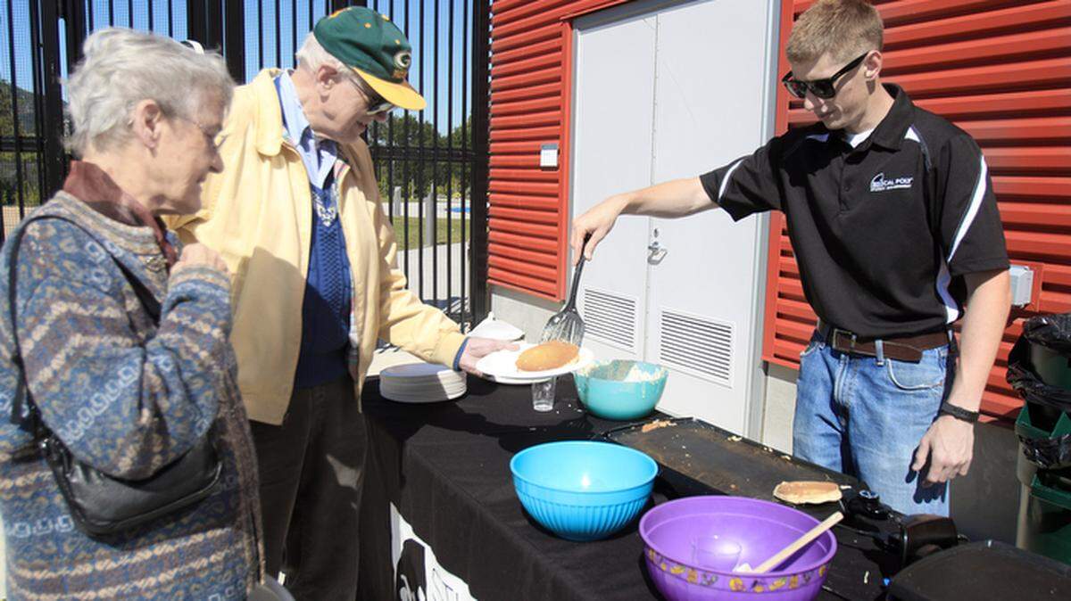 In an effort to build relationships between students and permanent residents in neighborhoods around Cal Poly, the Associated Students Inc. hosted a "Pedal to Pancakes" breakfast Saturday, May 16, 2015. Student Jake Rogers, right, serves pancakes to Olga and Jerry Howe.