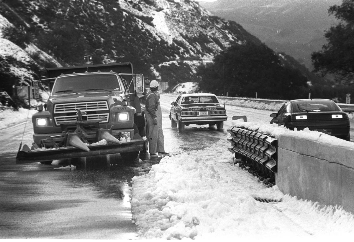 Terry Hetrick, a Caltrans equipment operator, waits for a grader to come across the road as the Calfornia Highway Patrol escorts traffic over the snow-topped Cuesta Grade on March 19, 1991.