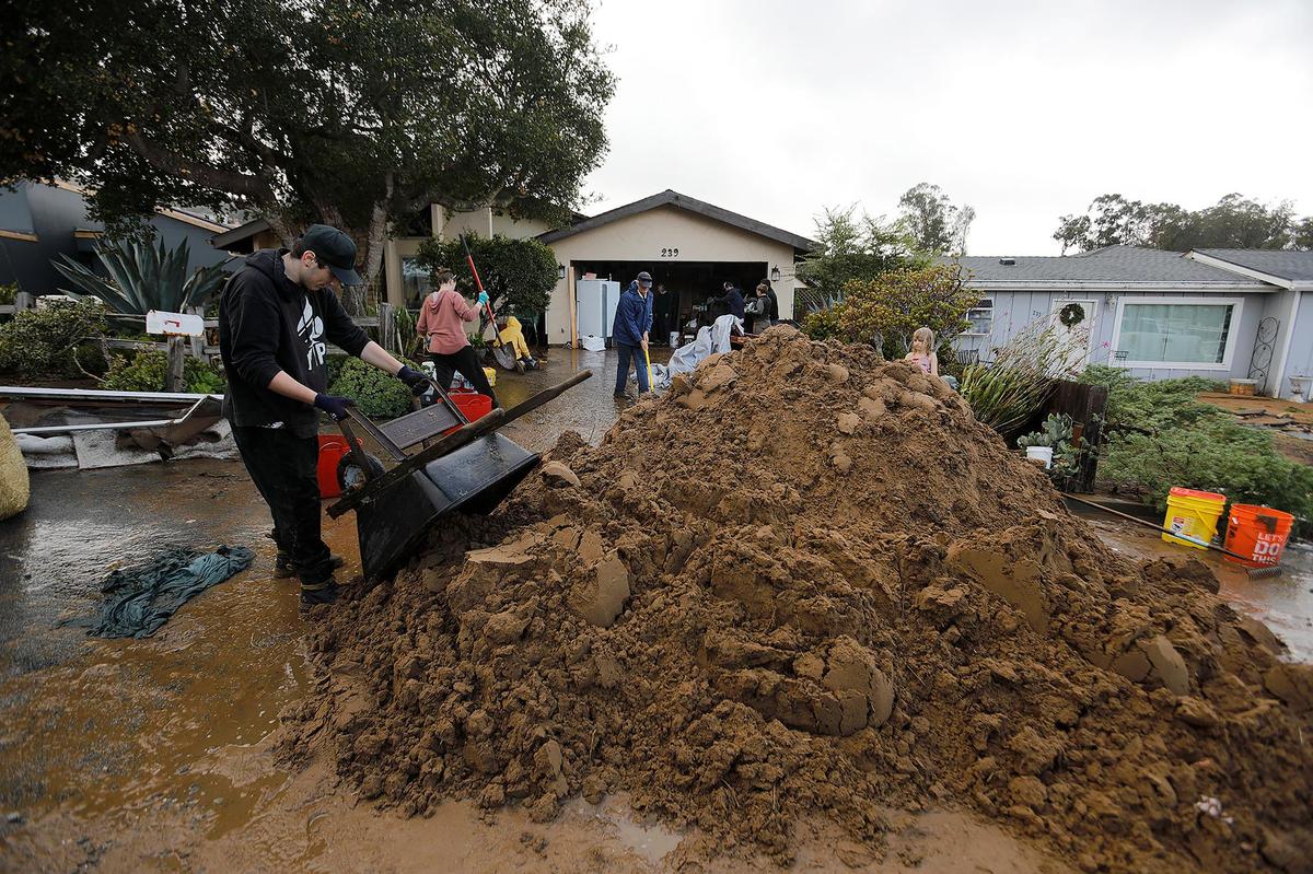 Homes on Vista Court in Los Osos were hit by water and mud Monday afternoon, causing devastating damage. Residents work to clean up a house on Jan. 10, 2023.