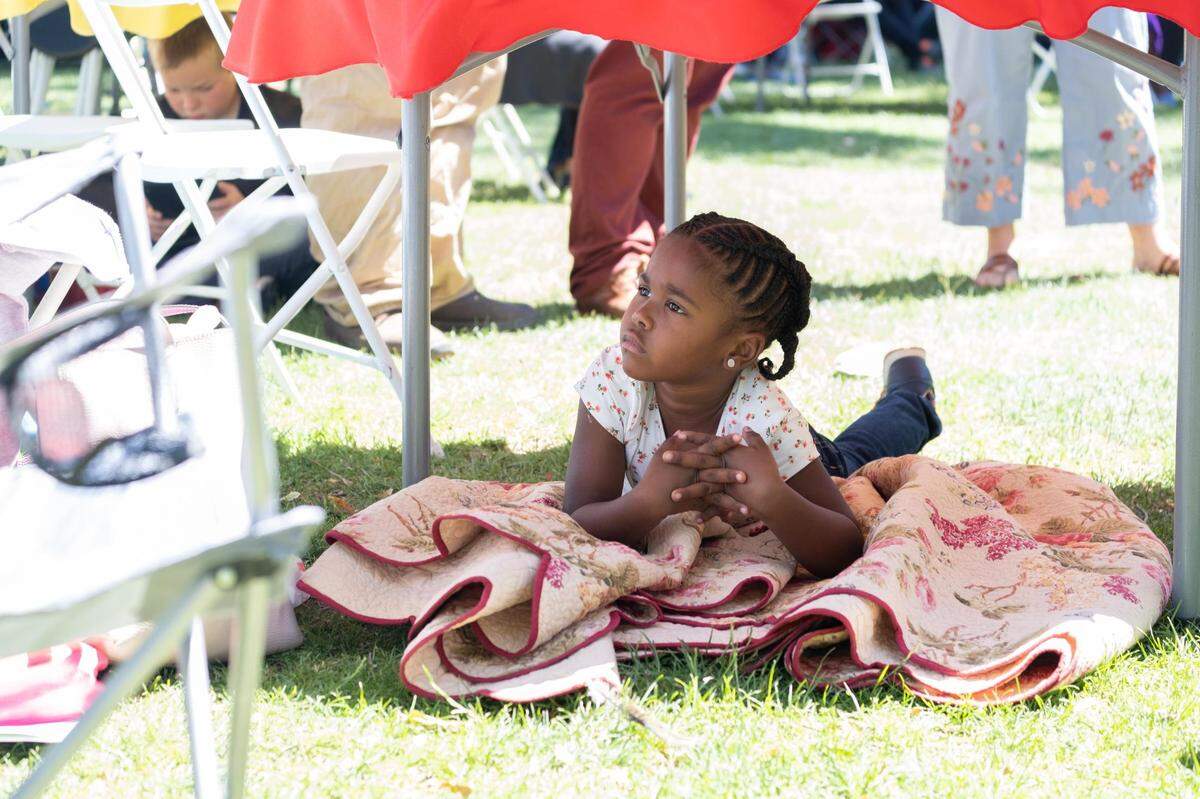 A child relaxes under a table at the Juneteenth Jubilee in downtown Paso Robles on June 18, 2022.