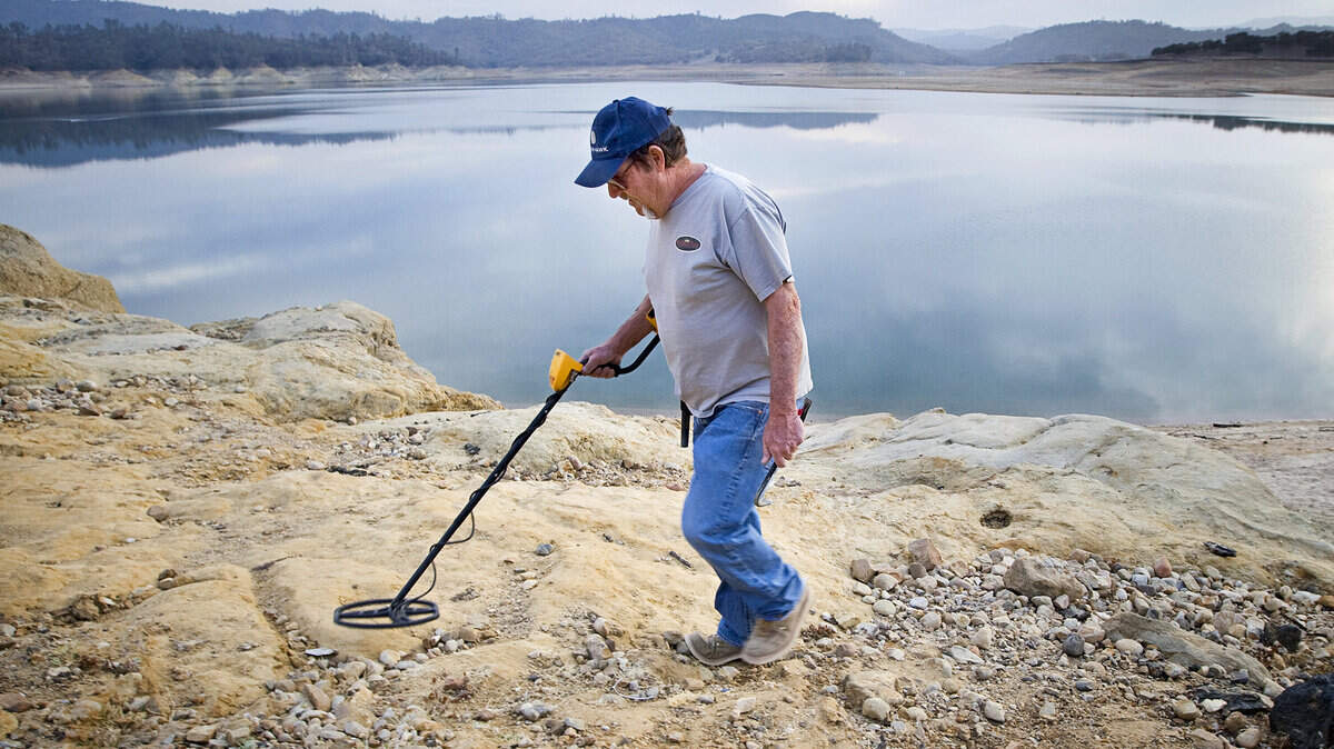 Doug Holloway, of Atascadero, uses a metal detector along the edges of Nacimiento Lake exposed by drought. He has found 20 rings so far this winter as well as fishing lures, coins and weights.