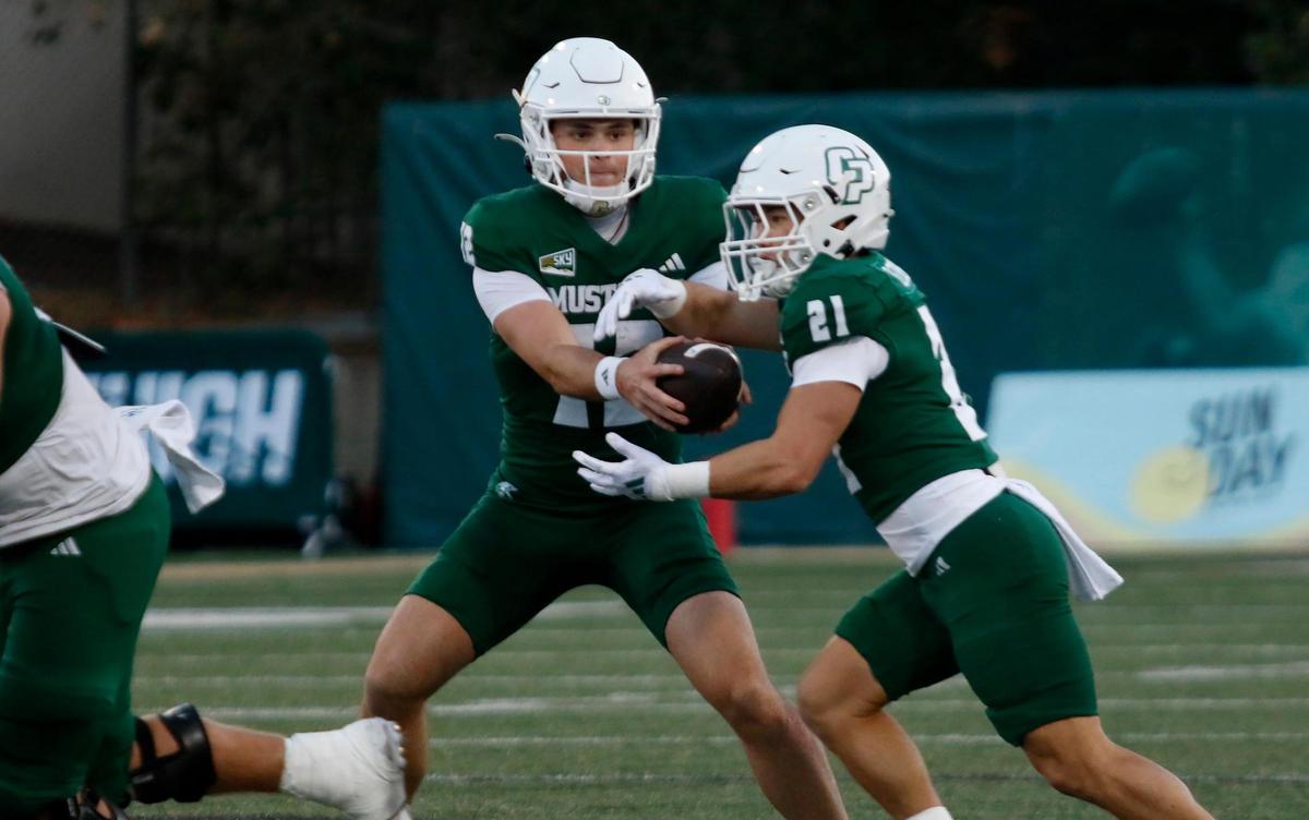Cal Poly quarterback Jackson Atkins does a play-action fake with running back Troy Fletcher. Cal Poly beat Sacramento State 26-23 in a college football game at Mustang Memorial Field on Nov. 16, 2024.