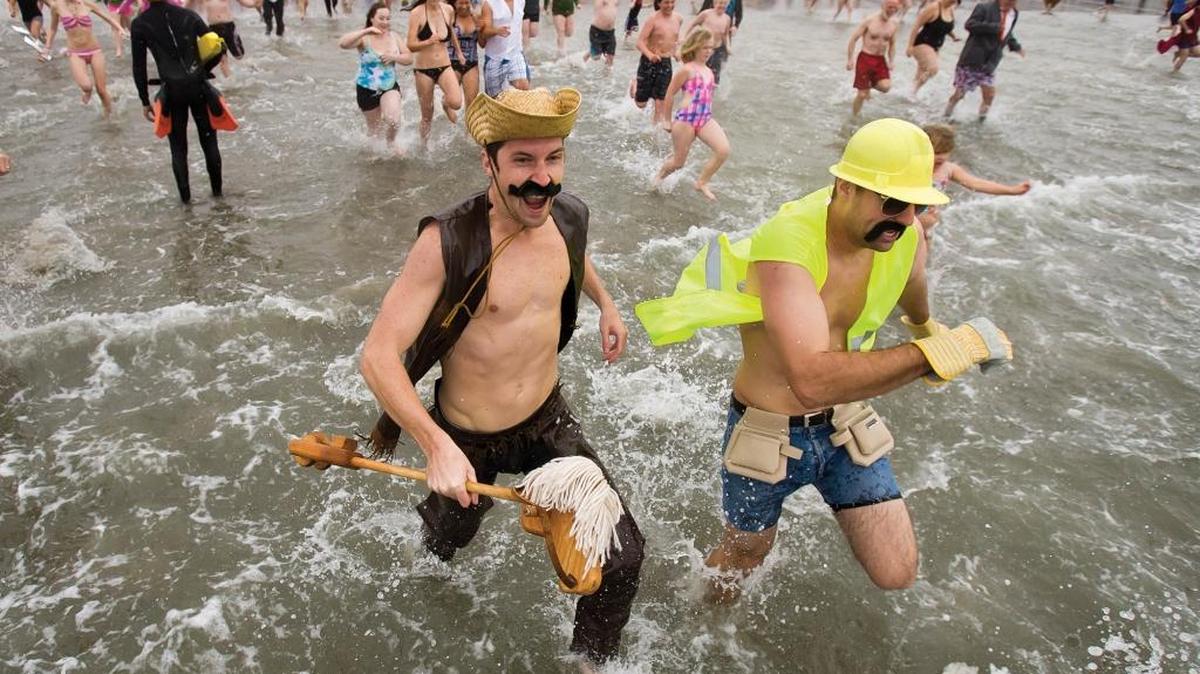 A pair of costume clad characters charge into the ocean during the 2011 Carlin Soule’ Memorial Polar Bear Dip at the Cayucos pier.