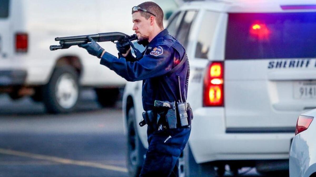 Police go through the parking lot of Excel Industries in Hesston, Kan., on Thursday, where a gunman killed several people and wounded dozens more, officials said.