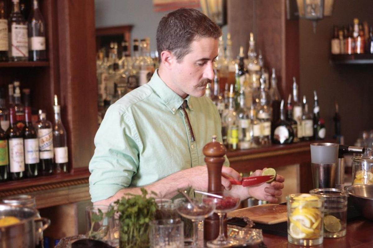 Sean Carroll, a bartender at Sidecar Cocktail Co. in San Luis Obispo, preps for the evening by cutting lemons and limes.