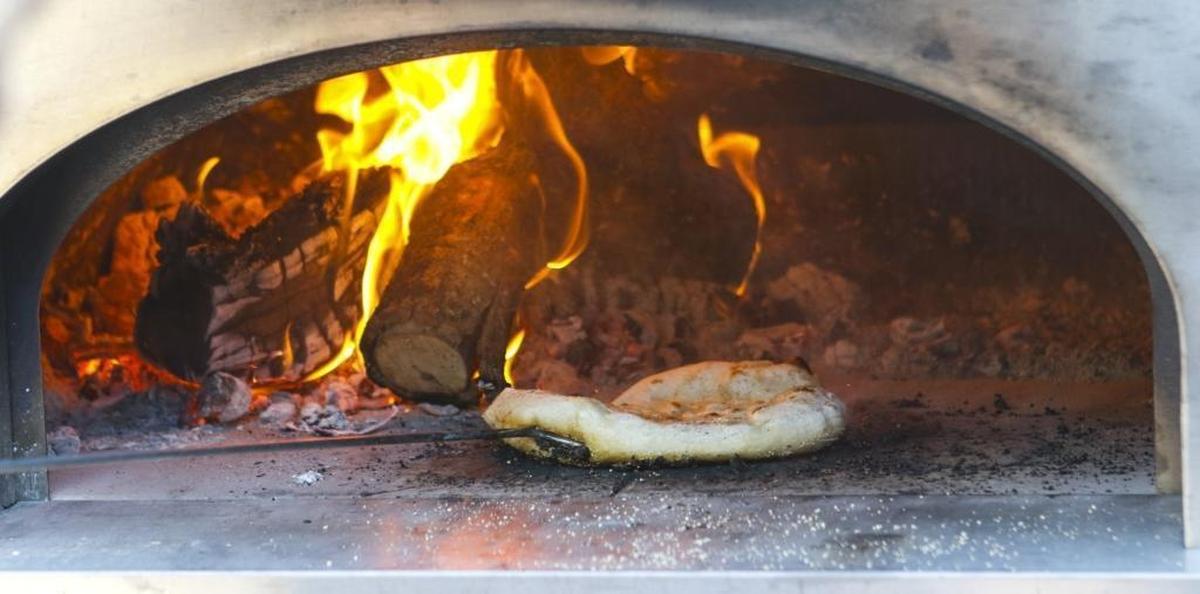 Pizza dough cooks in a wood-fired oven during an “Art of Artisan Pizza” cooking class at Refugio Kitchen in Paso Robles.