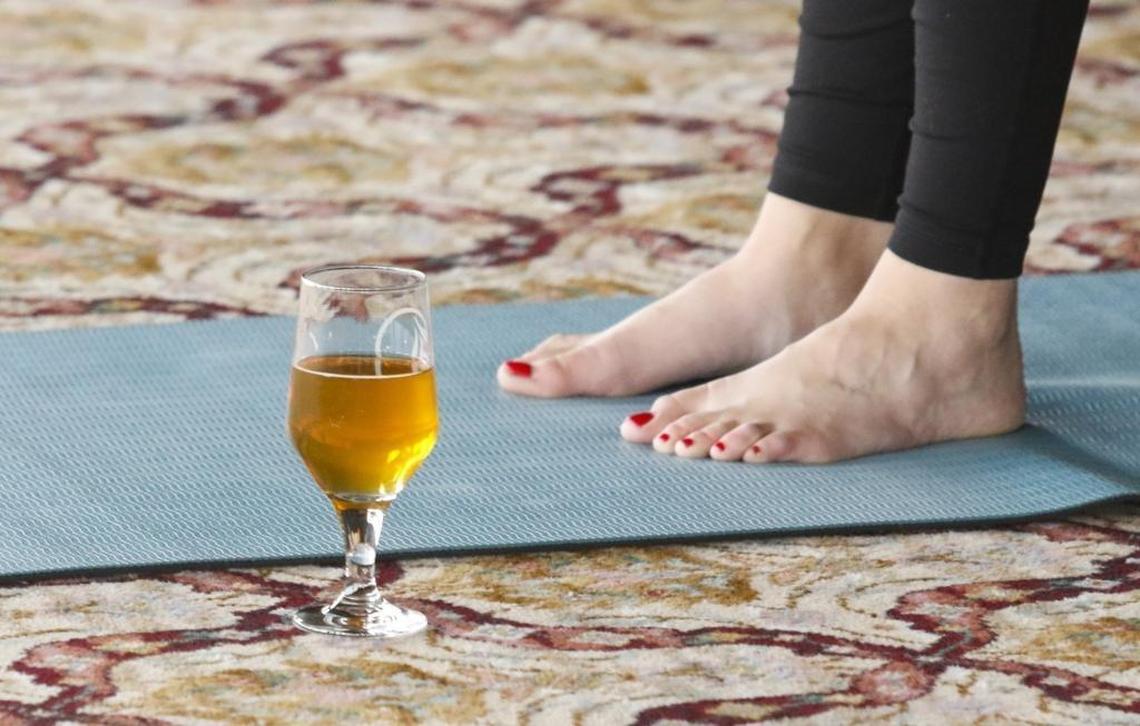 Participants do yoga poses with beer at the ready during a beer yoga class at the Libertine Pub in Morro Bay.
