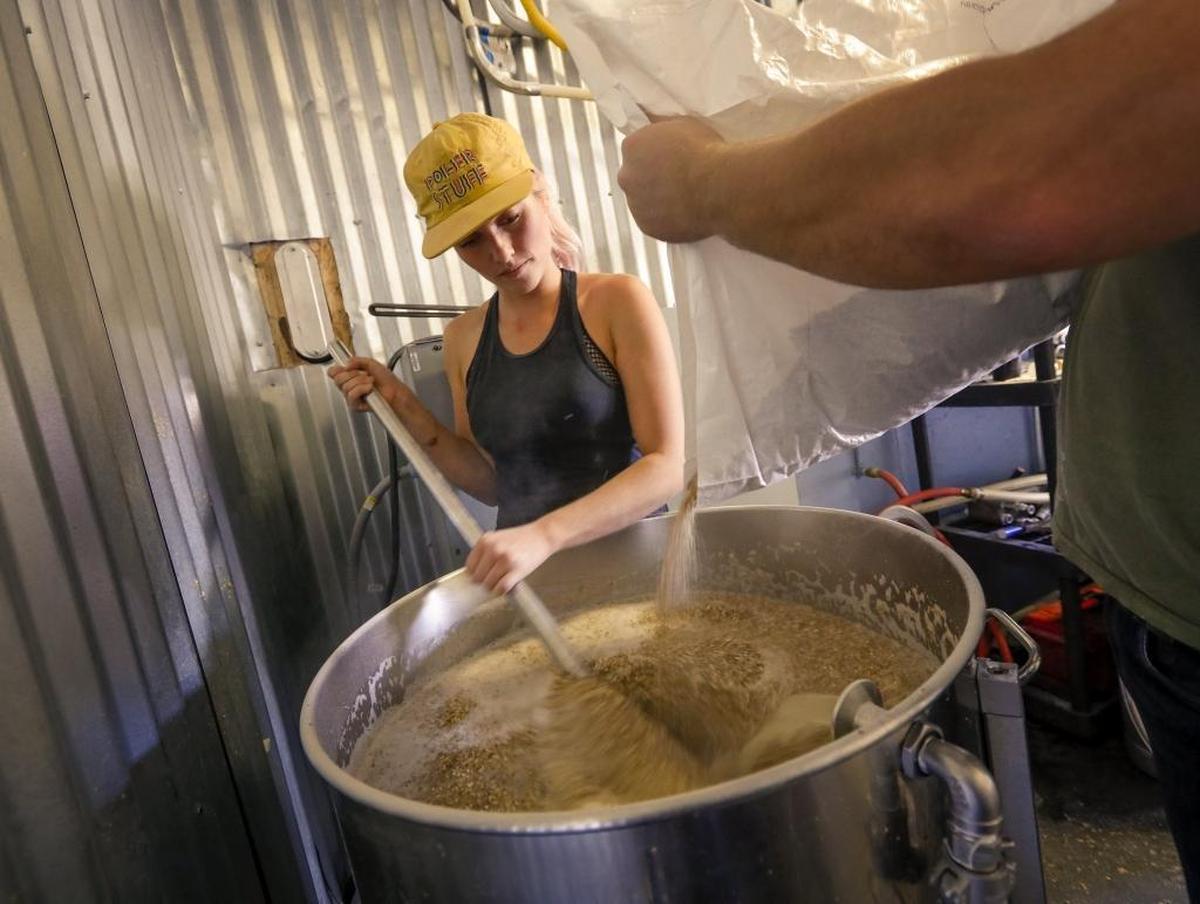 Kelly Edward, head brewer at Bang the Drum Brewery in San Luis Obispo, stirs in milled grain during the mashing-in process.