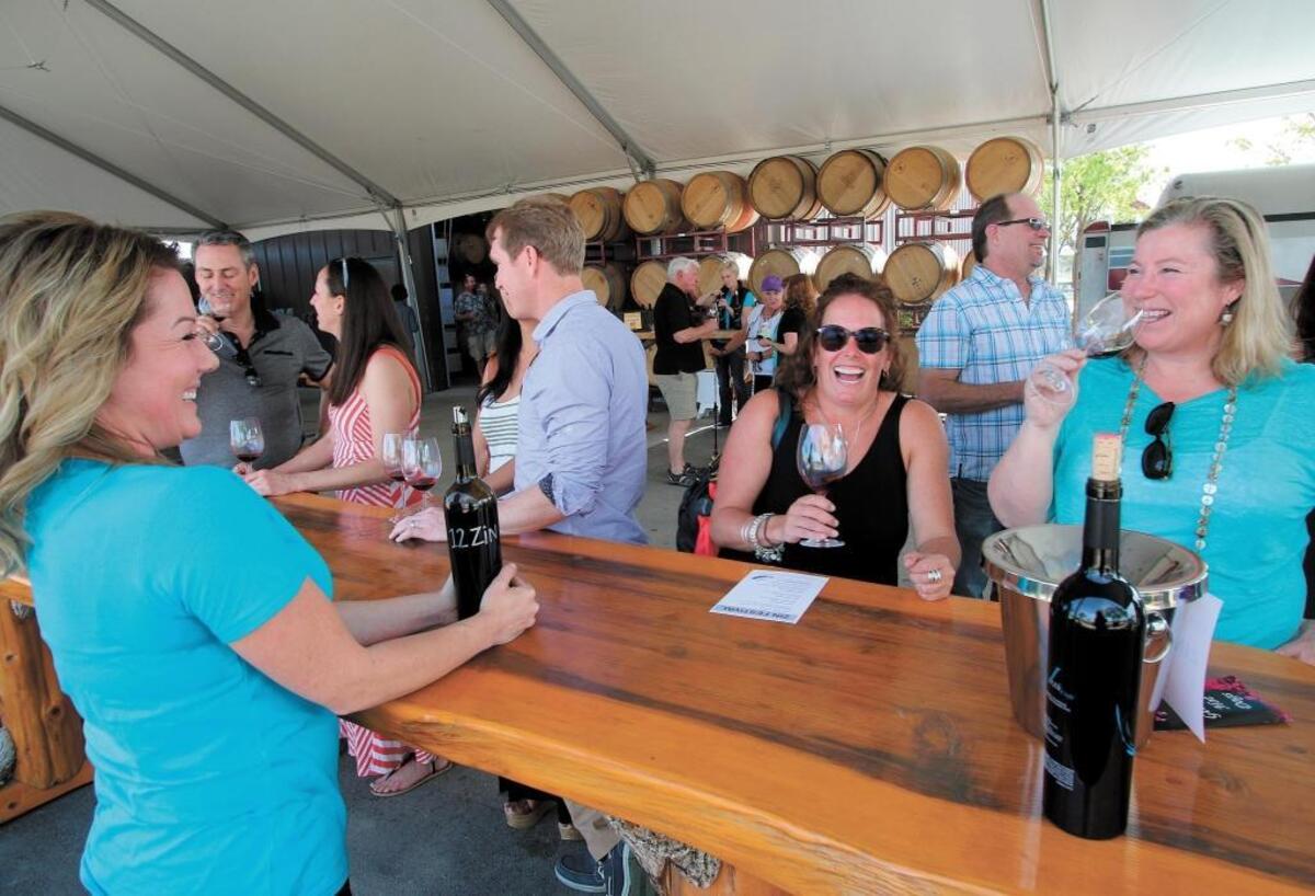 At the J Dusi Wines tasting room in Templeton, Jaime Christensen serves zinfandel to Katrina Dodson, center, and Carla Anderson, right, both of San Diego, during the Vintage Paso: Zinfandel Weekend in 2015. Organizers are scaling back Zinfandel Weekend events planned for March 2020 in Paso Robles.
