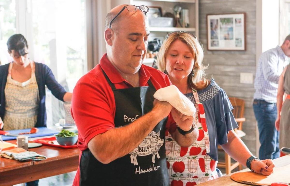 John Strube stretches out pizza dough as Teresa Strube observes during an artisan pizza cooking class at Brigit Binns’ Refugio Kitchen in Paso Robles.
