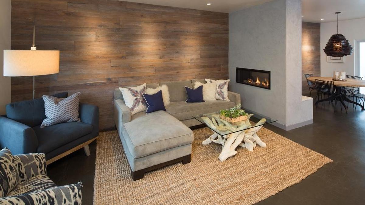 The living room combines ocean-inspired colors with a weathered wood wall. The coffee table’s driftwood base adds a touch of nature.