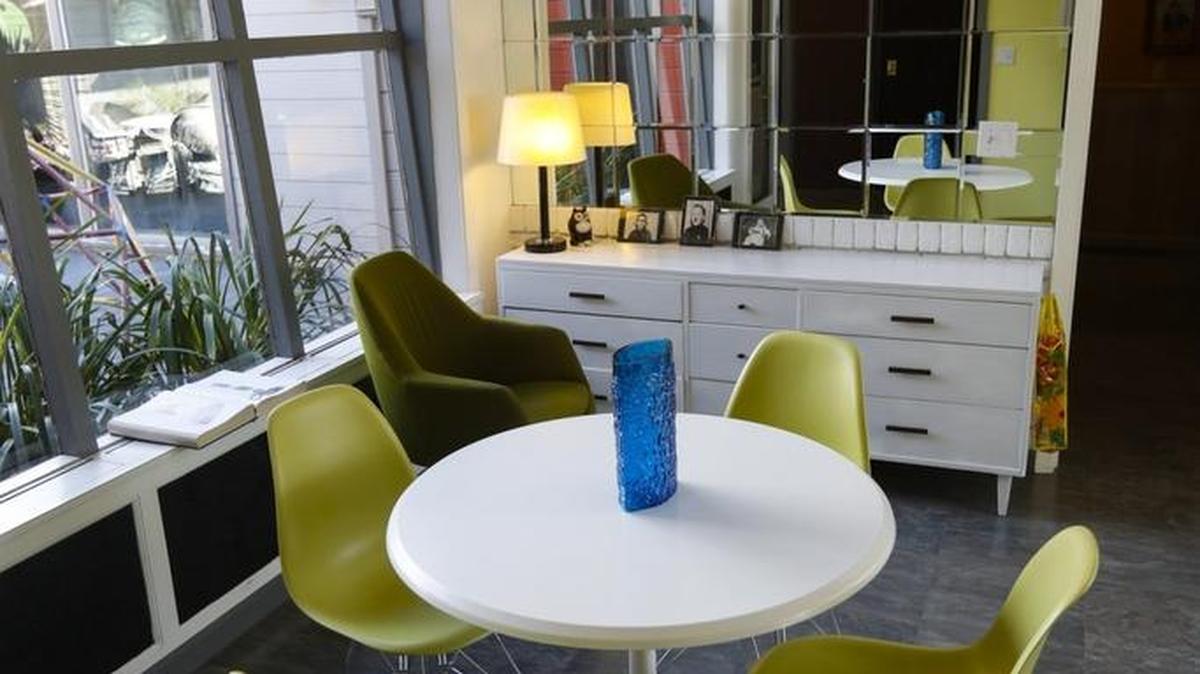 In the front room, a yellow accent wall repeats the color of a set of dinette chairs.