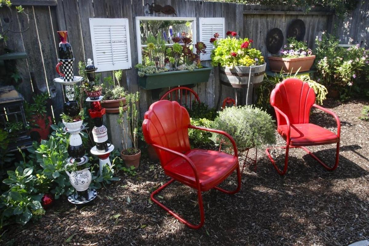 Red and black pottery and red chairs accent this section of the Thompson garden in Los Osos.