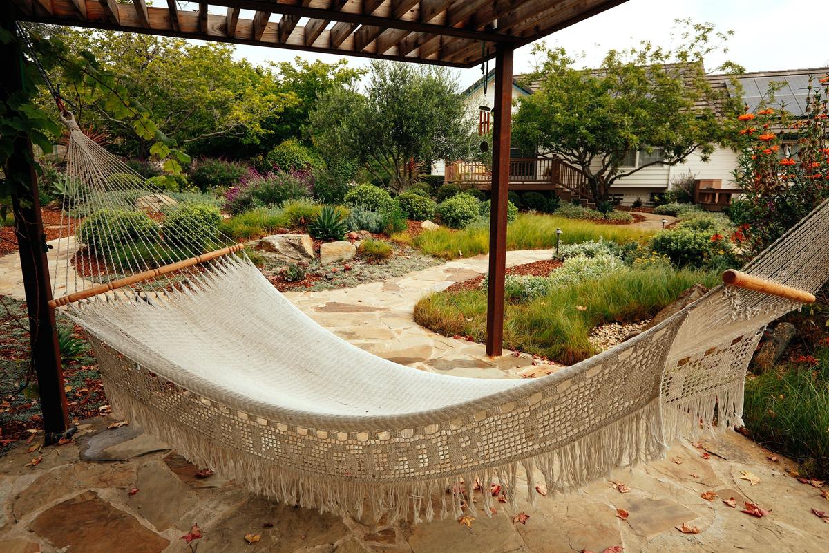 A hammock hangs under a metal and redwood pergola in an Arroyo Grande garden created by Purlieu Landscape Design and Build of San Luis Obispo.