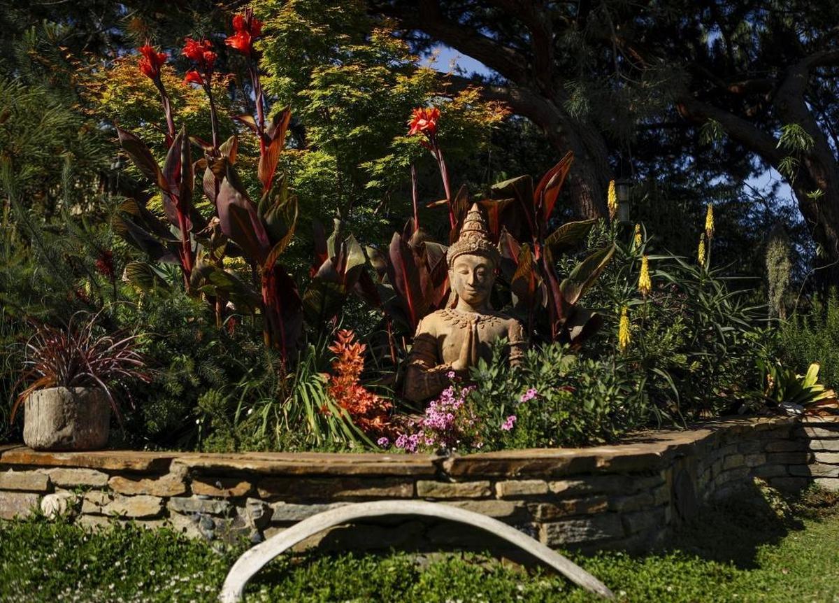 A tropical paradise is completed with an Asian sculpture. Greg Smith worked as a mason to build the low garden wall.