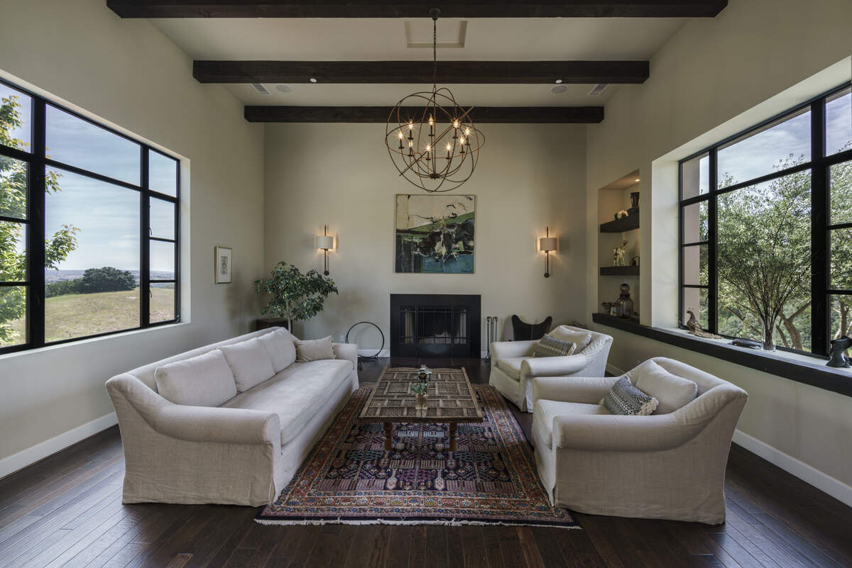 The living room of Varinder Sahi and Anita Kothari's Paso Robles home has two large picture windows, a 15-foot high open-beam ceiling and an open hearth wood-burning fireplace.
