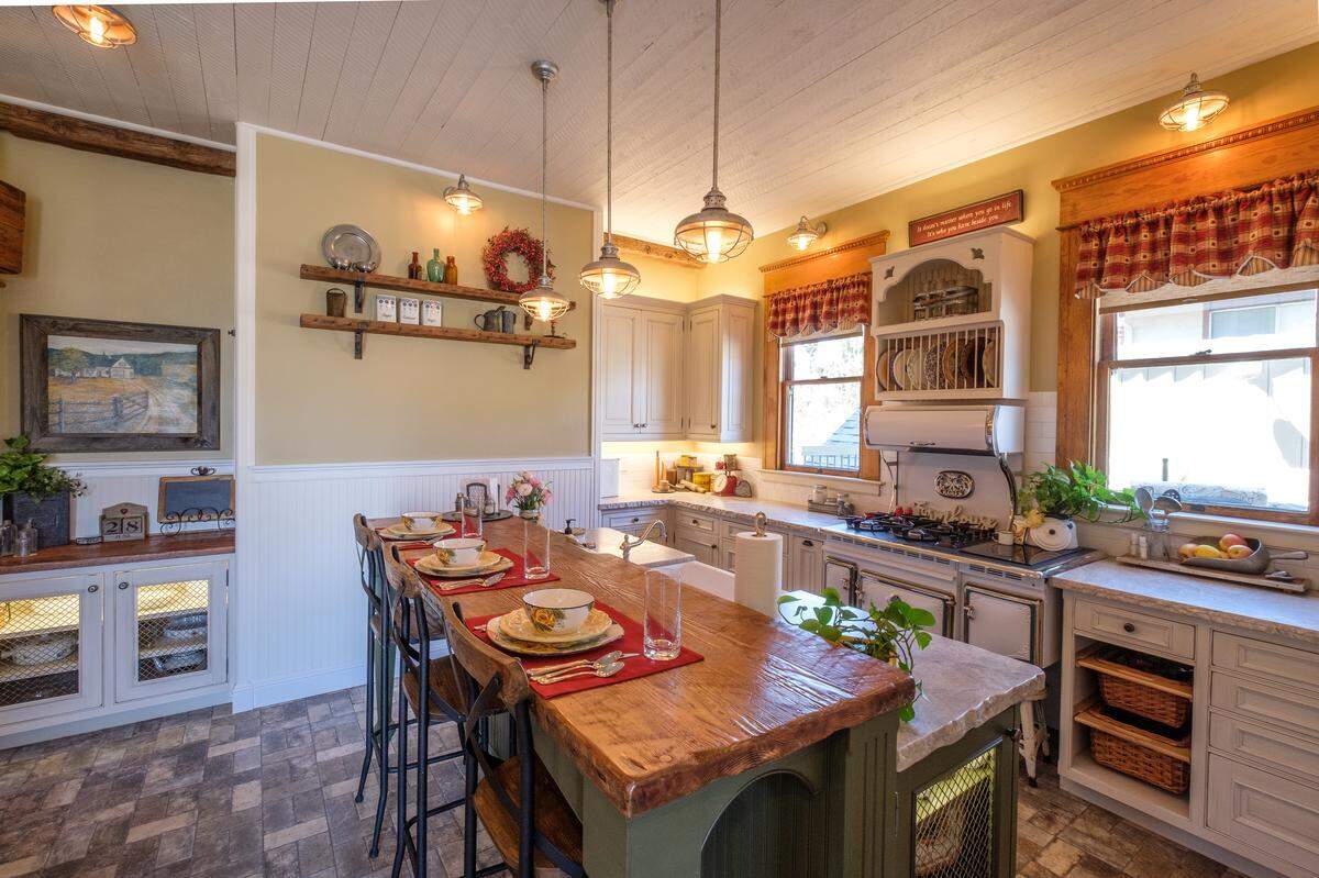 The renovated kitchen of the Stanton House in San Luis Obispo features custom handmade cabinets, leatherized quartzite countertops, rustic light fixtures and a vintage-style range.