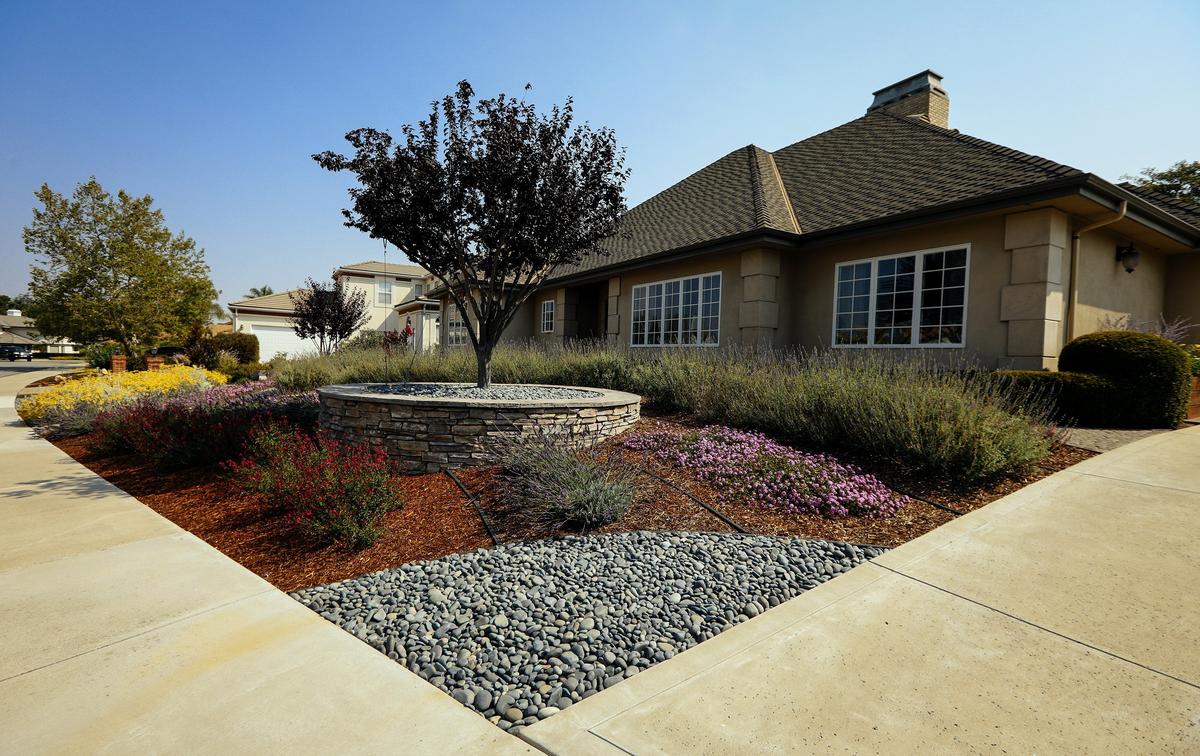 The front yard of Dale and Laura Texter’s San Luis Obispo home features curved flowerbeds, stacked-stone planters and cobblestone paths.