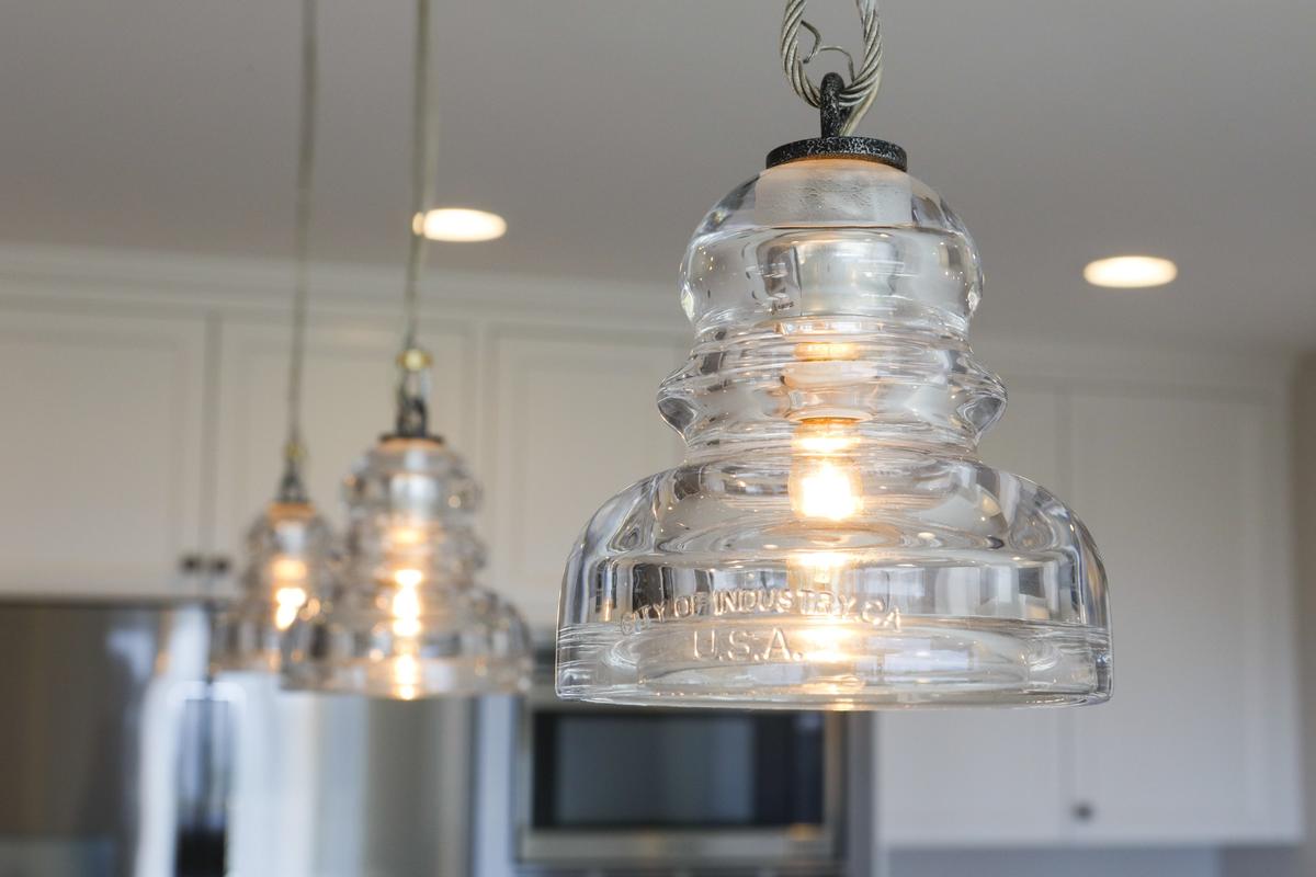 A light fixture made of electrical insulator glass suspended from stainless steel cable hangs in the kitchen of John and Diane Somers’s Cambria home.