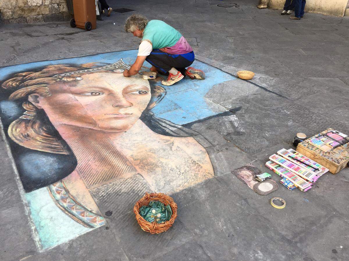 An artist puts the finishing touches on a street painting in Siena, Italy.