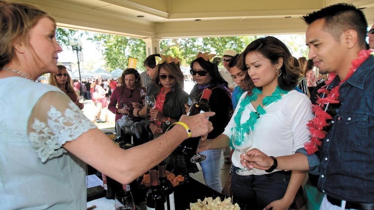 Paso Robles wineries joined together in May 2015 to showcase their wines at the Grand Tasting in downtown Paso Robles City Park. Linda Parker Sanpei, pouring for the Paso Robles CAB Collective, pours a cab franc for Rosemary Canilao and Russell Manuyag of East Valley, California. Sanpei paired all their wines with a special cheese.