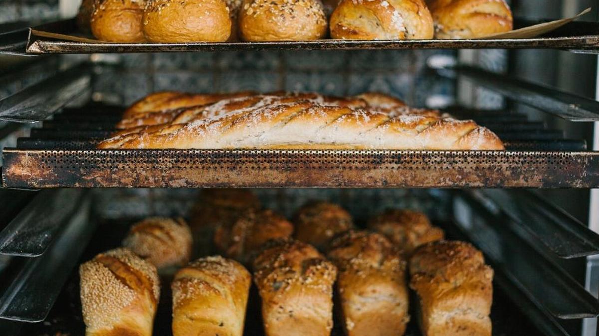 A batch of fresh bread in a bakery oven.
