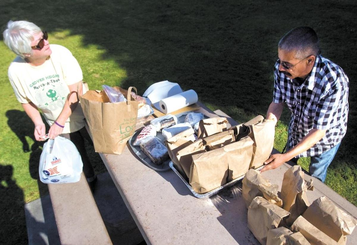 Betsy Ehrler and volunteer Charles Florez set out lunches for the South County People’s Kitchen clients.