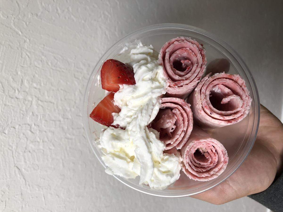 A dish of Rolld ice cream is served with whipped cream and strawberries.