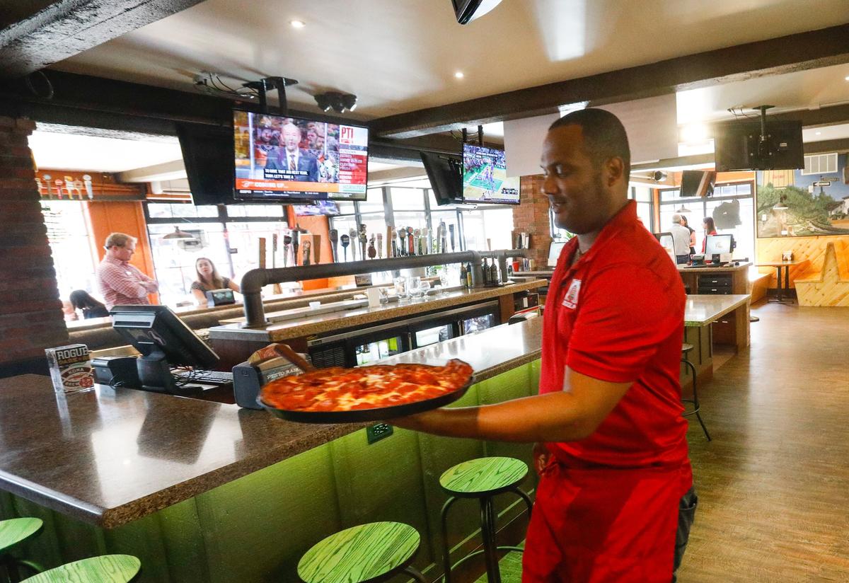 Darryl Turner serves a pizza at Woodstocks, which just completed a renovation of its dining room.