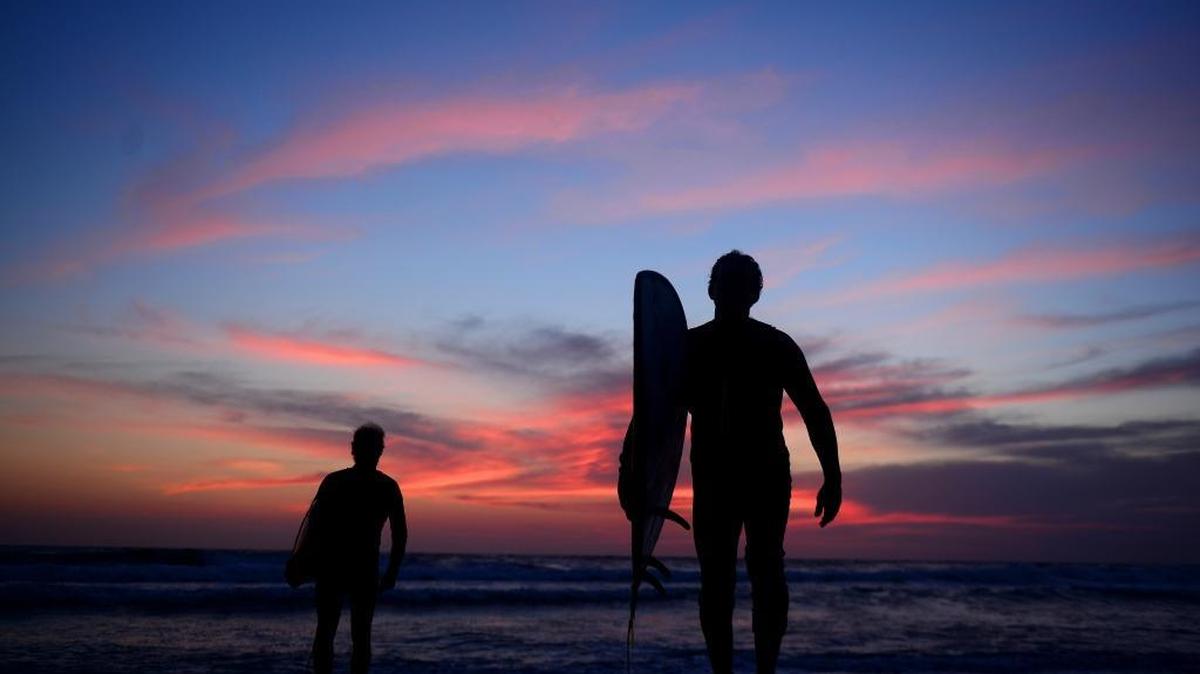 Helmut Igel and James McDonald prepare to paddle out into the surf near San Diego on April 10, 2017. Igel is among a small subculture of surfers who dot coastlines from San Diego to Sydney after sunset, pursuing an adventure that’s a subject of curiosity on social media these days thanks to pro surfers on LED boards.