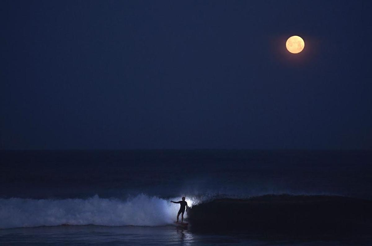 Helmut Igel surfs under a full moon near San Diego on April 10, 2017.