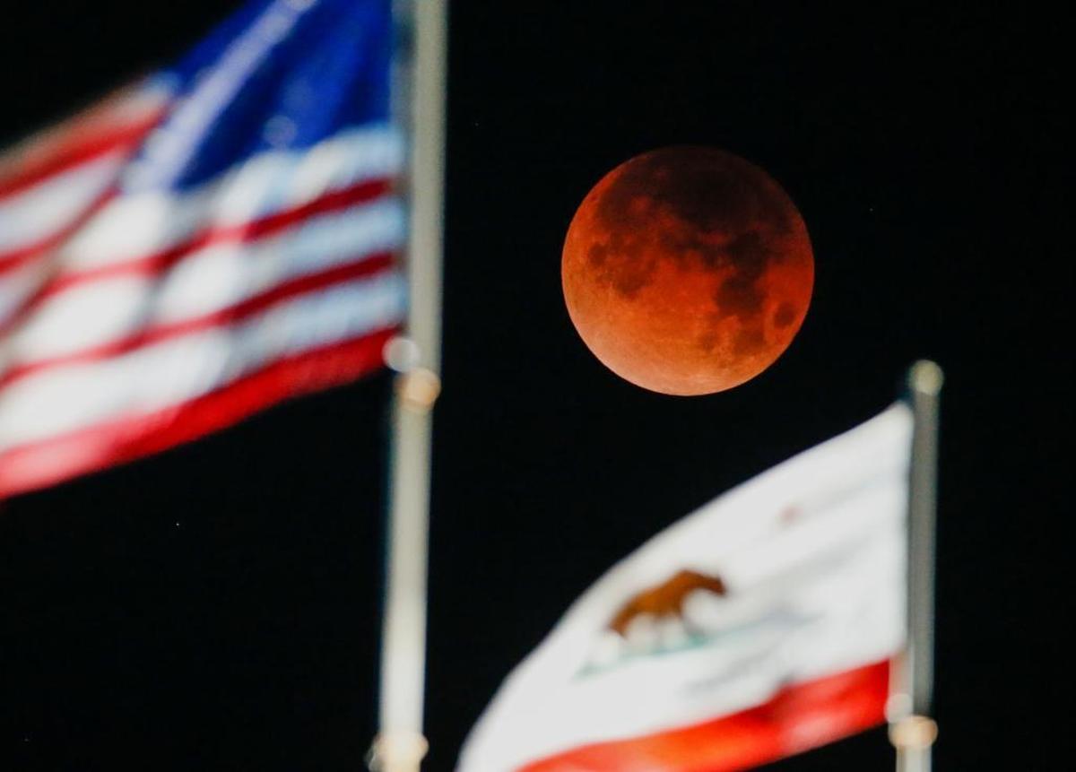 The super blue blood moon seen behind the U.S. and California flags in Santa Monica, California, on Jan. 31, 2018.