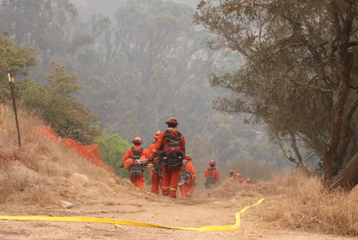 A prison firefighting team works to create a fuel break and hose line Thursday, December 14, 2017, near San Ysidro Creek to guard agains the spread of flames to nearby residences.
