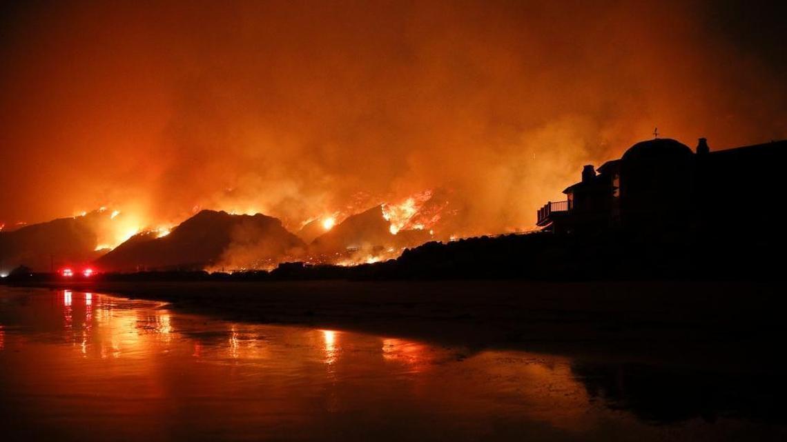 In this file photo from December 5, 2017, the Thomas Fire burns along Highway 101 in Ventura, California. The huge wildfire that burned hundreds of homes in Santa Barbara and Ventura counties is now the largest in California’s recorded history.