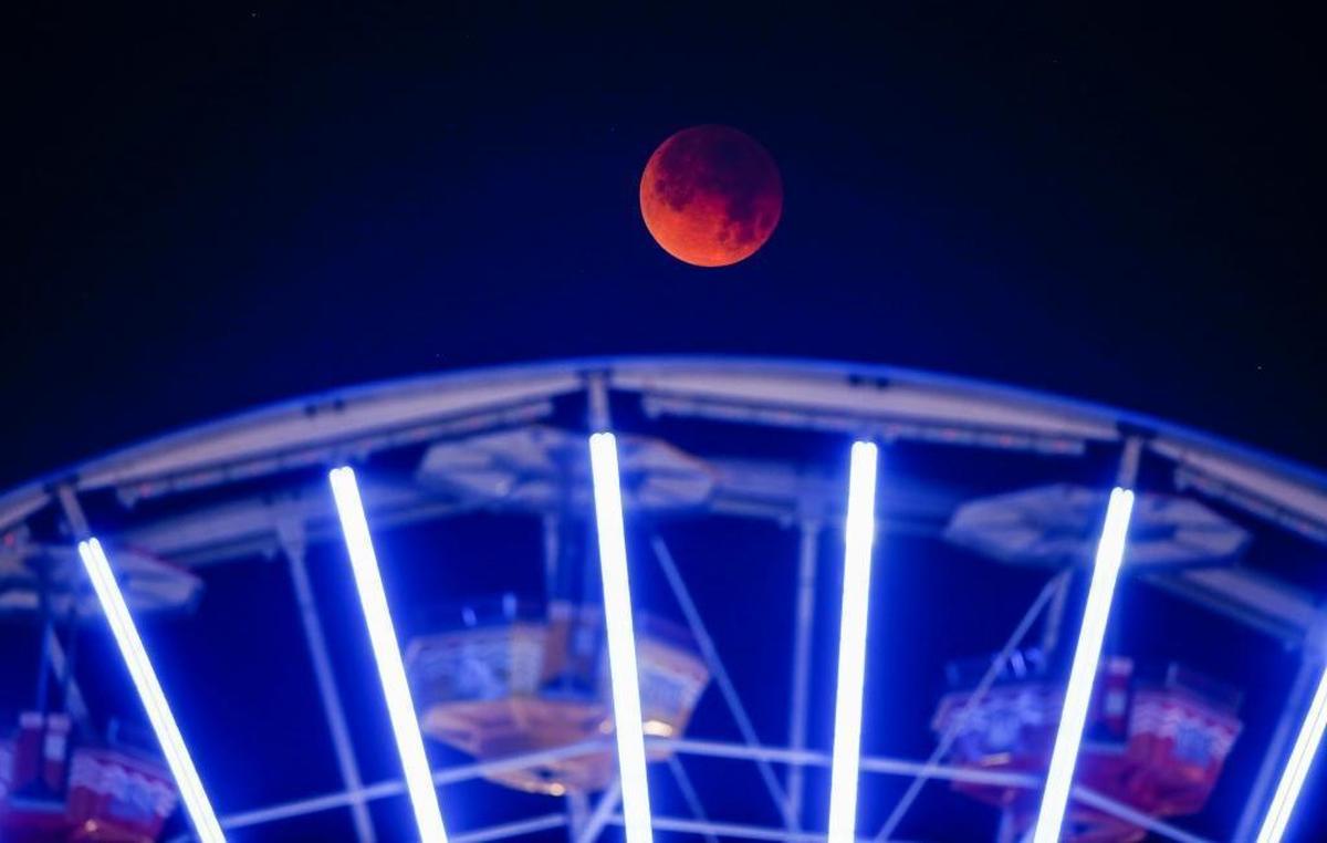 The super blue blood moon seen behind a ferris wheel at the Santa Monica Pier.