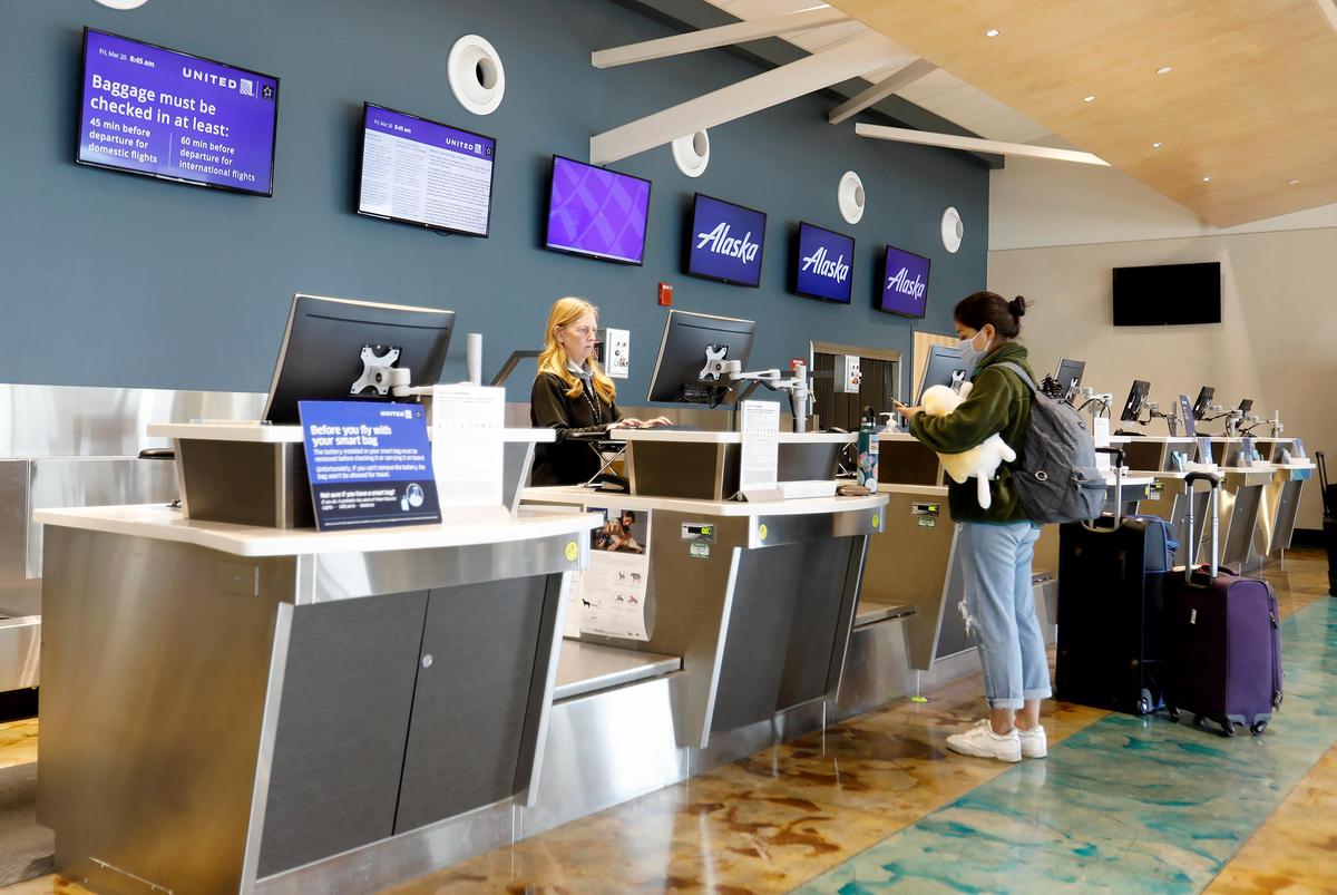 A passenger wearing a mask checks in for a flight at San Luis Obispo County Regional Airport, which has seen a major slowdown in air travel amid coronavirus precautions.