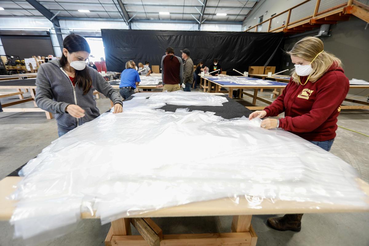 Rosie Daniels, left, and Mary Sylvestre prepare plastic protective gowns for shipping. Daniels Wood Land in Paso Robles typically creates playground equipment, movie props and tree houses. Due to the coronavirus outbreak, the company has shifted gears to produce plastic gowns for emergency workers and hospitals.