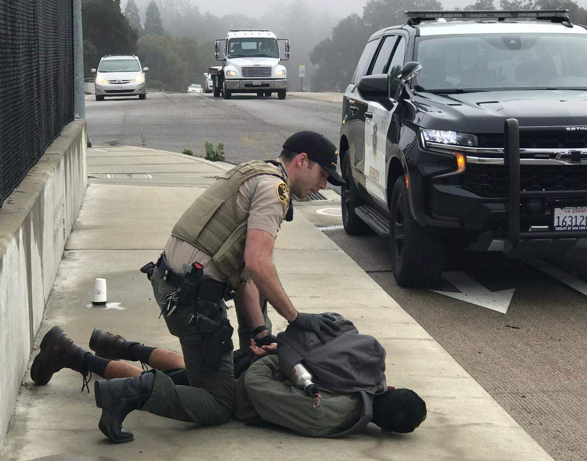 A sheriff’s deputy arrests Miguel Angel Olivares of Arroyo Grande after Olivares pepper-sprayed a group of “pro-democracy” demonstrators on the Vineyard Drive highway overpass in Templeton on Sept. 20, 2022.