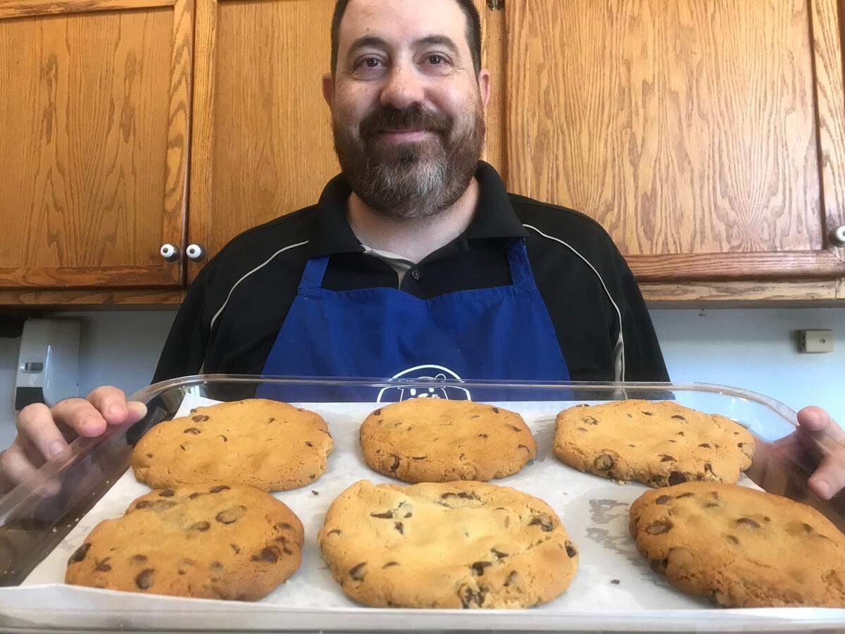 David Montemayor, sales associate at Blue Shell’s Sweets & Treats in Morro Bay, shows off a tray of the shop’s popular chocolate chip cookies.