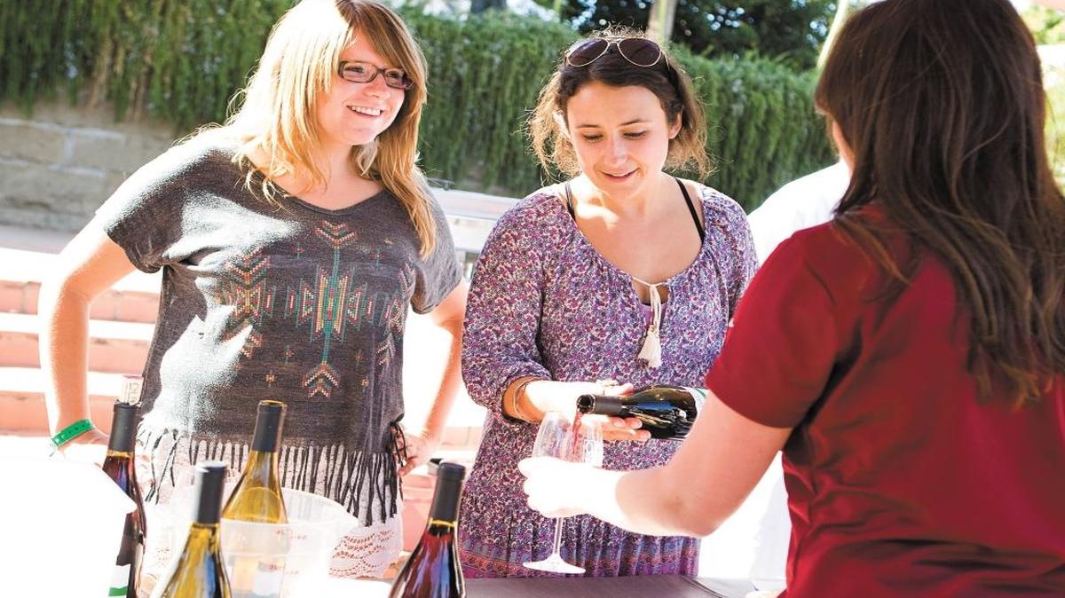 Kelly Allyn, left, and Ella Johnson pour Cal Poly-made wine at a Roll Out The Barrels event at the Mission Plaza in June 2014.
