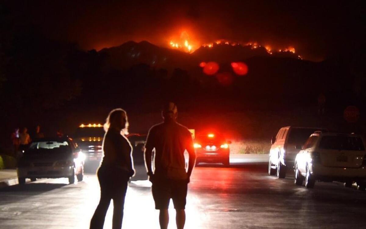 People watch flames from the Whittier Fire from Winchester Circle on Thursday night in Goleta.