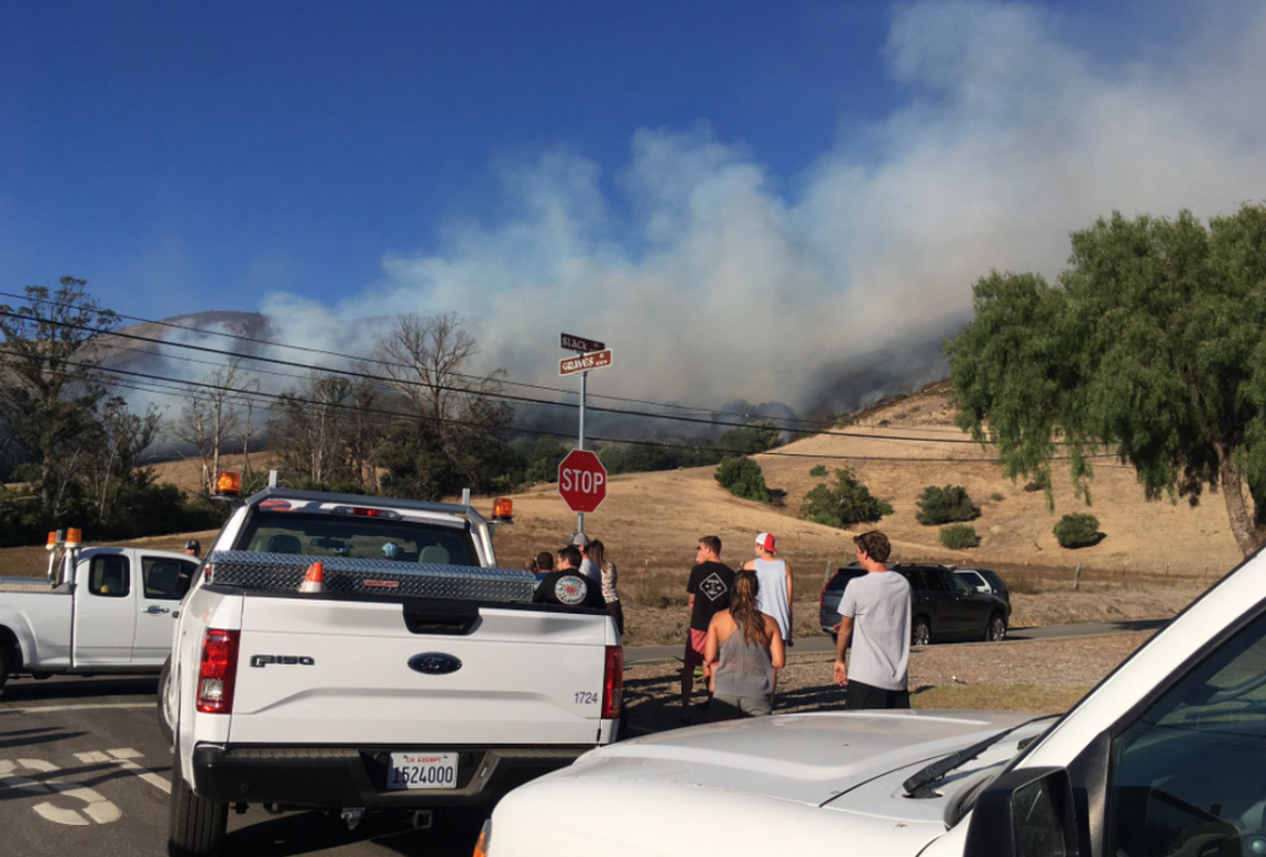 Students gather at the corner of Slack Street and Graves Avenue to watch the progress of the fire burning Tuesday, Sept. 26, 2017, on the hillside above Cal Poly.