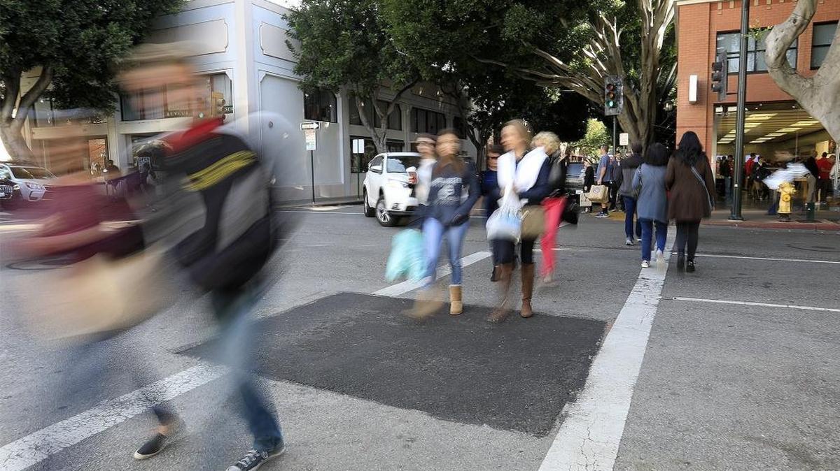 People walk across Higuera Street in downtown San Luis Obispo for some last-minute Christmas shopping Saturday, December 23, 2017.
